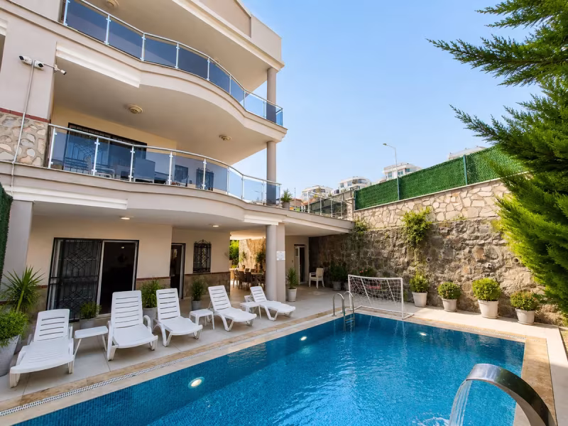 Yenilenen villa cephesi, havuz, teras ve taş duvarlı bahçenin genel görünümü