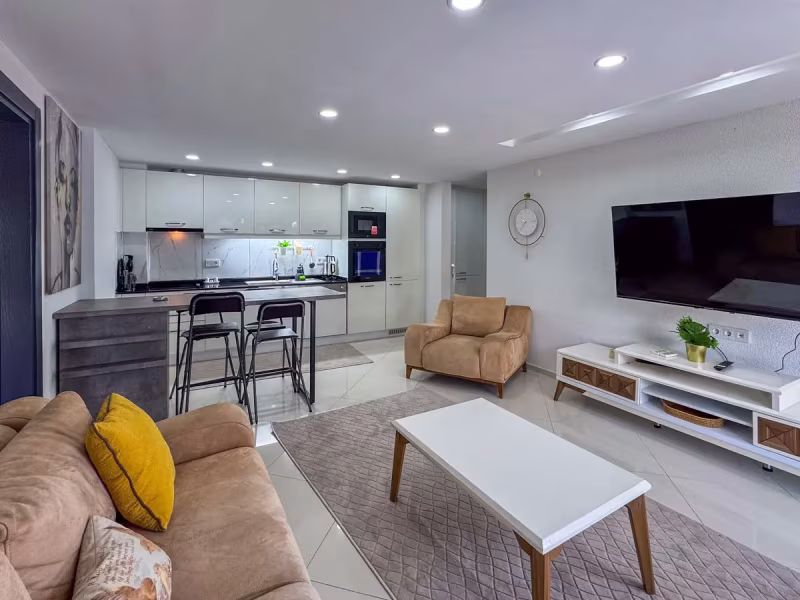 Yenilenen açık plan salon ile beyaz mutfağın birlikte görünümü