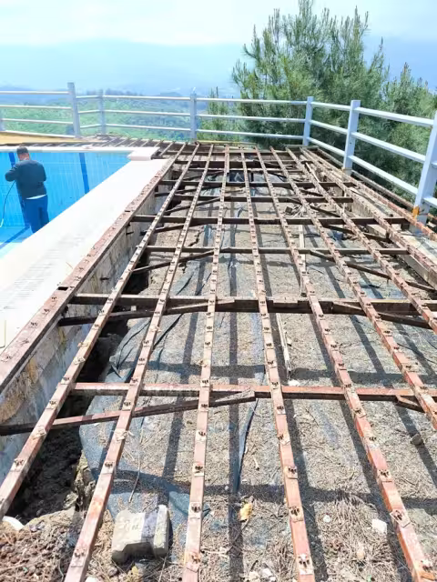 Sökülen havuz deck kaplamasının altında görülen metal karkas ve bitki kökleri